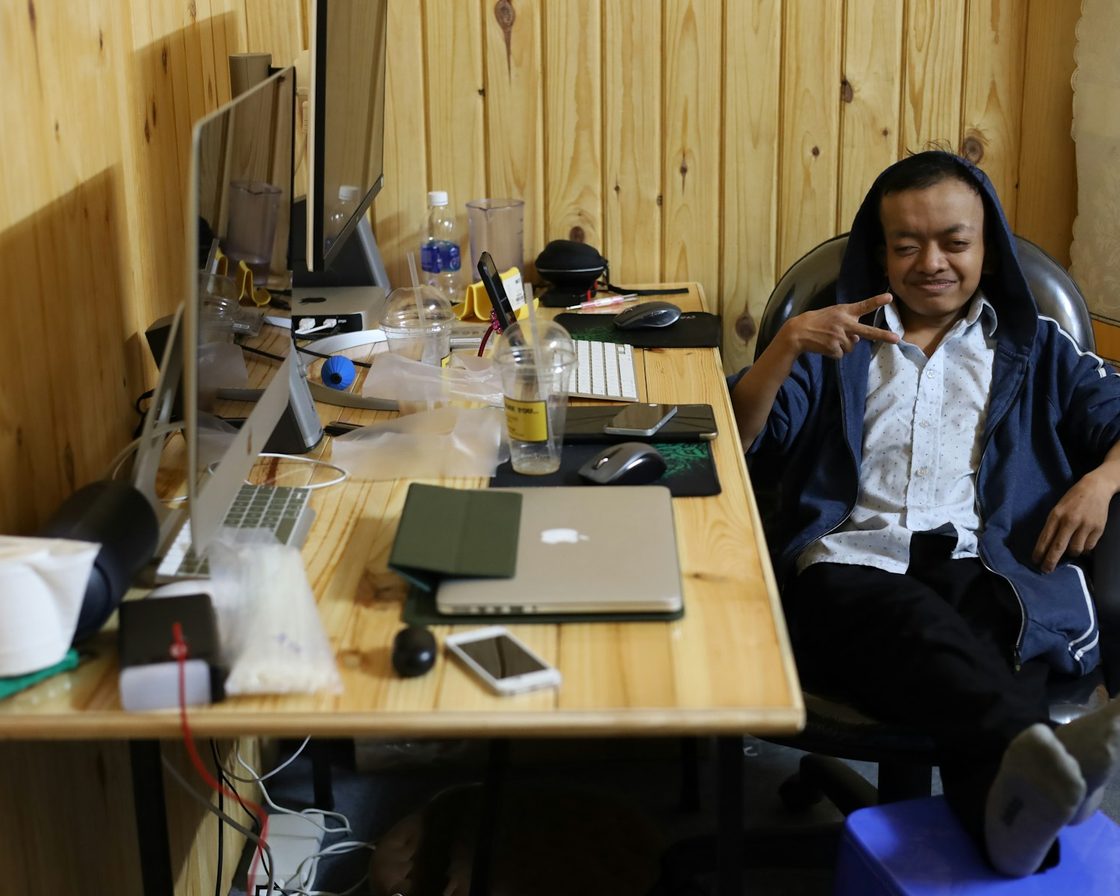 Pemilik usaha duduk di meja kerja dengan laptop dan dua monitor, menghitung pajak badannya