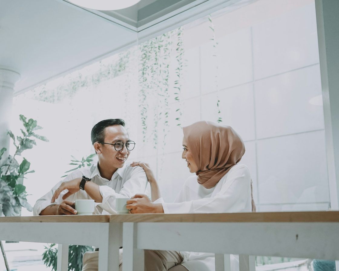 Pria berkacamata dan perempuan berhijab berbincang di meja kantor, membahas perubahan aturan pajak
