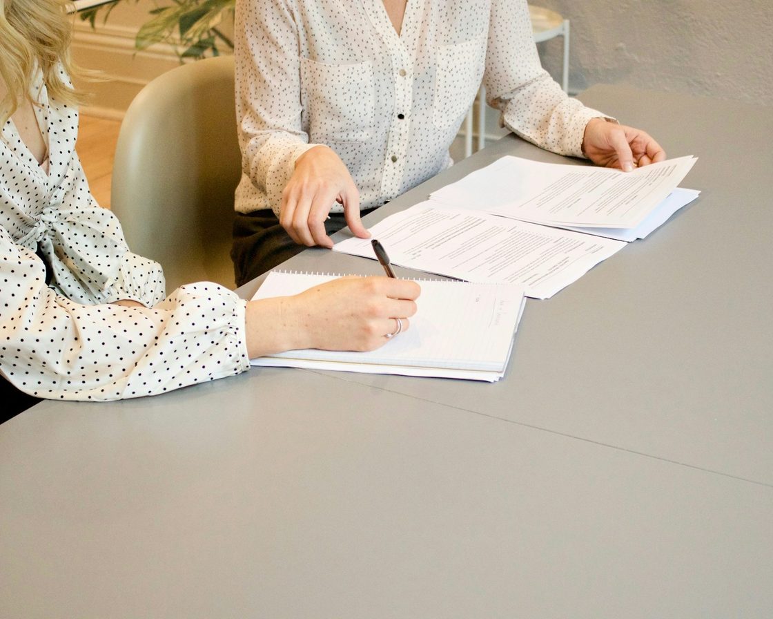 Perempuan membaca dokumen dengan saksama di meja kantor