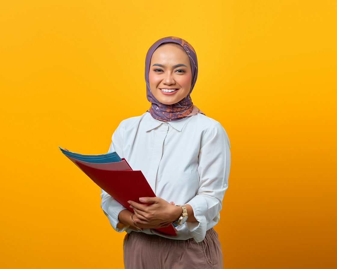 Konsultan perempuan berhijab memegang map dokumen dan tersenyum
