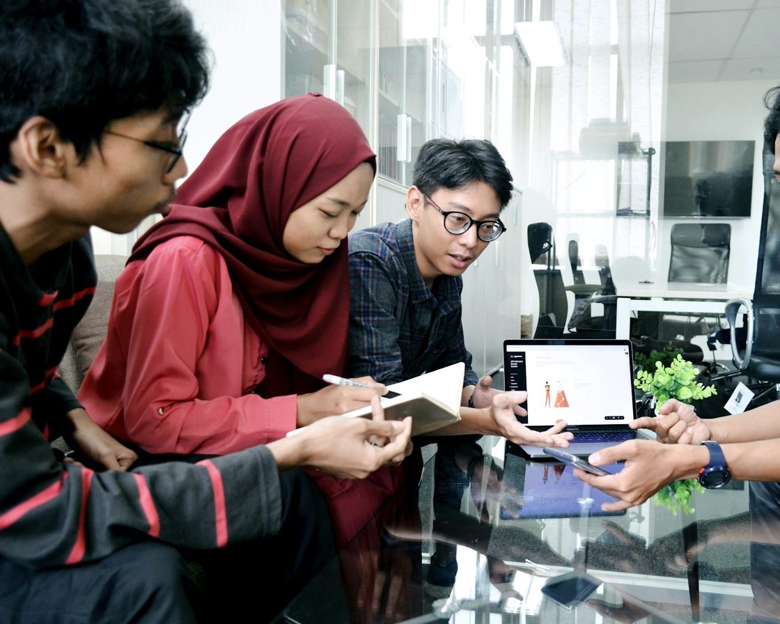 Rekan kerja berdiskusi di depan laptop sambil mengikuti panduan