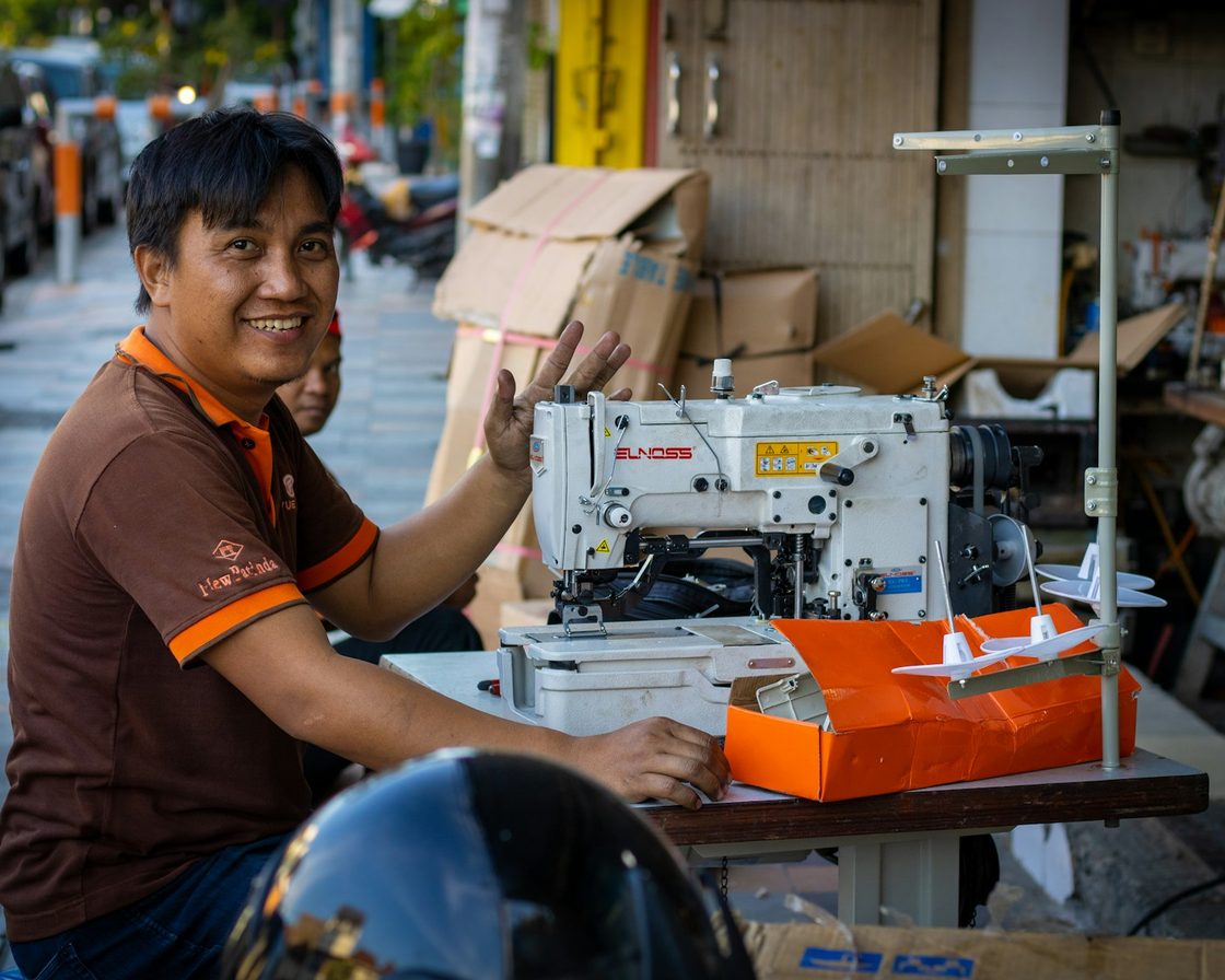Penjahit di depan mesin jahit di ruang usahanya, contoh pengusaha yang bisa dikukuhkan PKP