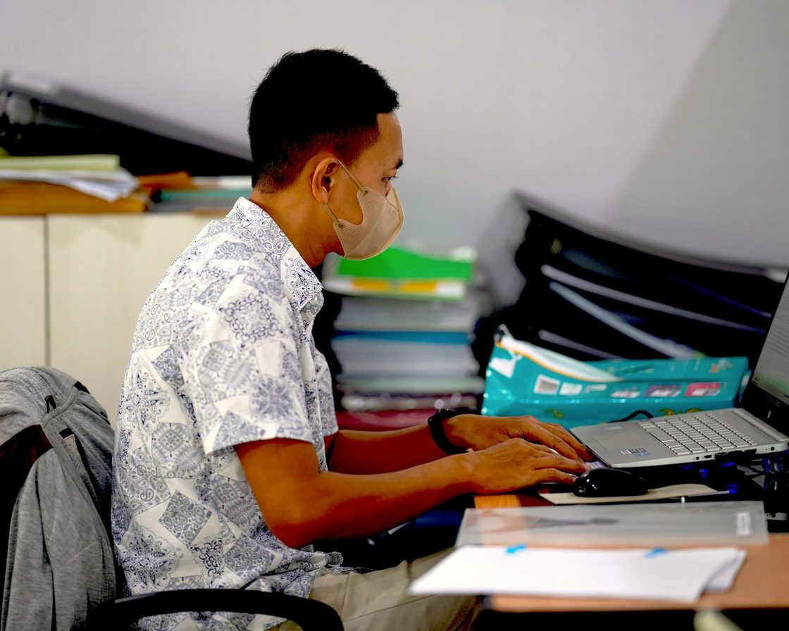 Pria di meja kerja menelaah berkas SPT di antara tumpukan map
